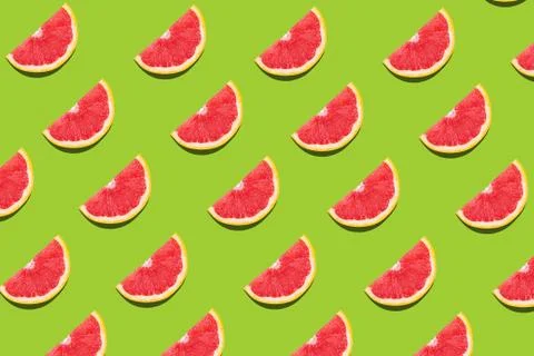 Flat lay fruit pattern of fresh grapefruit slices on green background. Stock Photos