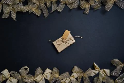 Flat lay of gift box and golden gift bows on dark background. Stock Photos