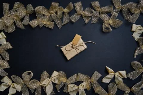Flat lay of gift box and golden gift bows on dark background. Stock Photos
