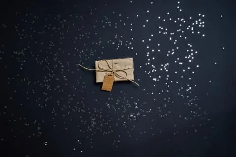 Flat lay of gift box and silver glitter sparklings on dark background. Stock Photos