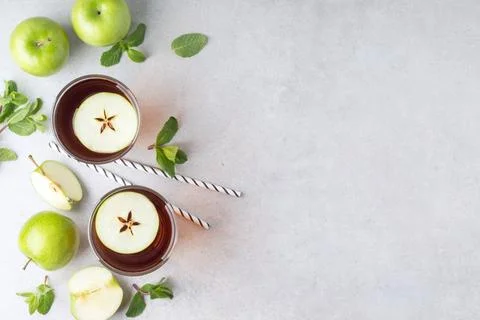Flat lay with glasses of fresh apple juice and green fruits on grey table, .. Stock Photos