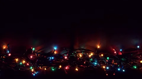 Flat lay glowing Christmas lights with copy space on dark plank background. Stock Footage 143909797