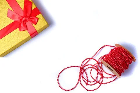 Flat lay with a gold gift box with a red bow and a red strass chain for decor Stock Photos
