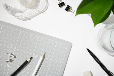 Flat lay of gray cutting mat with pencils, push pins, tape, binder clips, pen 스톡 사진