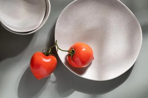 Flat lay of gray monochrome plates and tomatoes. Culinary concept  Stock Photos
