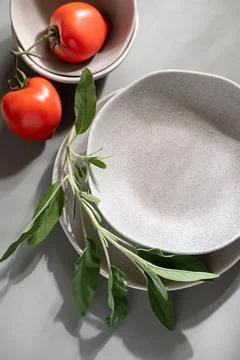 Flat lay of gray monochrome plates with sage. Stock Photos