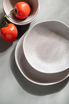 Flat lay of gray monochrome plates and tomatoes. Culinary concept  Stock Photos