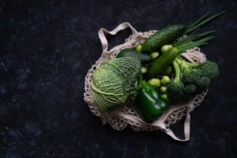 Flat lay of green vegetables in textile shopping bag. Raw fresh organic Stock Photos