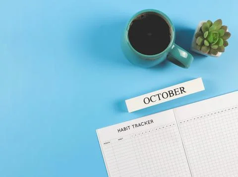 Flat lay of habit tracker book, wooden calendar October,  blue cup of black c Stock Photos