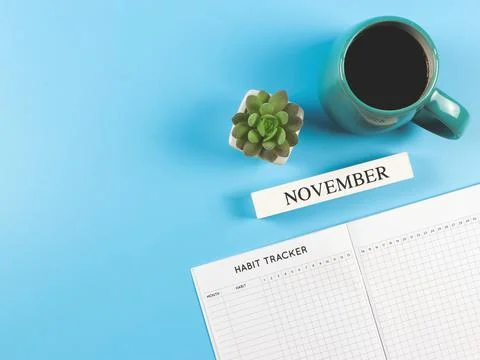 Flat lay of habit tracker book with  wooden calendar november, blue  cup of b Stock Photos