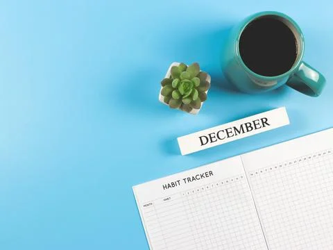 Flat lay of habit tracker book with  wooden calendar december, blue  cup of b Stock Photos