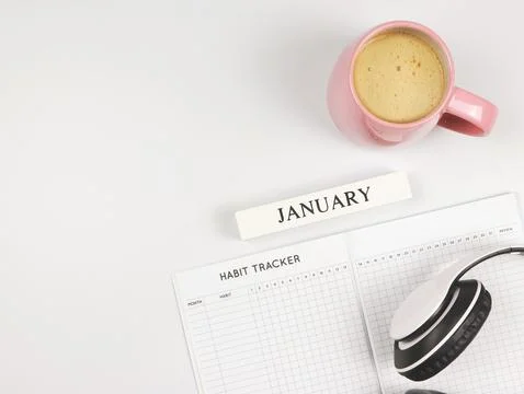 Flat lay of habit tracker book, wooden calendar January, pink cup of coffee.. Foto stock