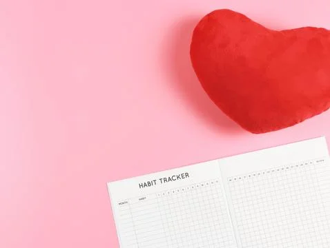 Flat lay of habit tracker book with  red heart shape pillow on pink  backgr.. Stock Photos