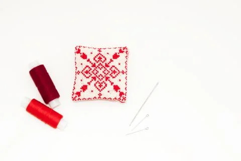 Flat lay with handmade red embroidered needle pad, thread spools, pins, needl Fotos de archivo