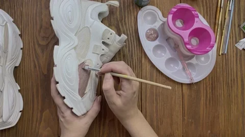 Flat lay of hands paint white boots with brush on desktop. Stock Footage 164127902