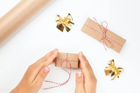Flat lay on hands tying a red thread on Christmas gift package, isolated on Stock Photos