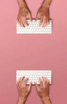 Flat lay with hands typing on white key board on pink table Stock Photos