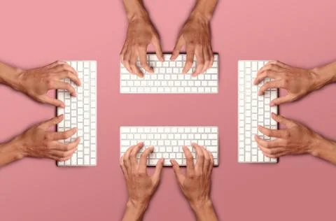 Flat lay with hands typing on white key board on pink table Stock Photos