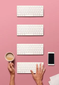Flat lay with hands, white key board, track pad, smartphone and coffee on pin Stock-Fotos