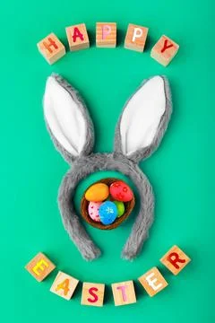 Flat lay of Happy Easter wooden blocks, fluffy bunny ears, and a nest of co.. Stock Photos