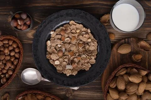 Flat lay of healthy breakfast with nuts and corn flakes on brown rustic backg Stock Photos