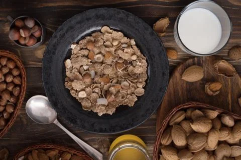 Flat lay of healthy breakfast with nuts and corn flakes on brown rustic backg Stock Photos