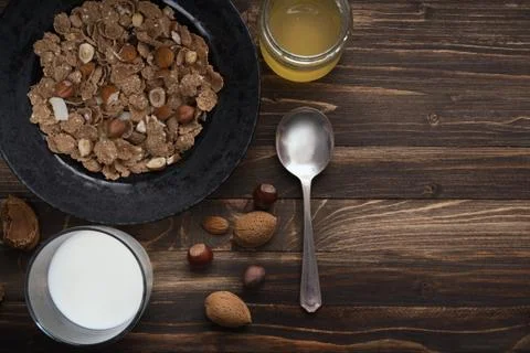 Flat lay of healthy breakfast with nuts and corn flakes on brown rustic backg Stock Photos