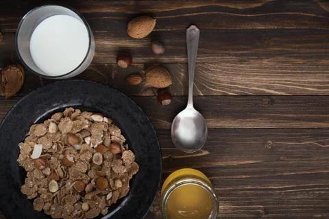 Flat lay of healthy breakfast with nuts and corn flakes on brown rustic backg Stock Photos