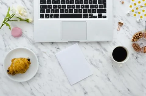 Flat lay hero header on marble background with laptop, croissant and office Stock Photos