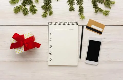 Flat lay of holiday gift, notepad, cards, and phone on table Stock Photos