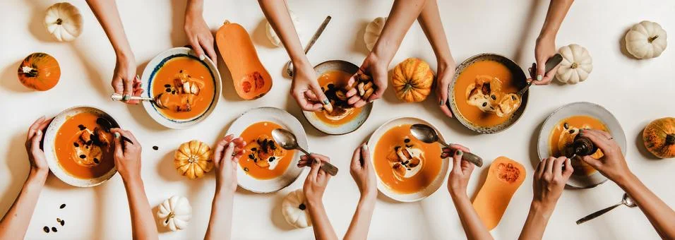 Flat-lay of human hands having lunch with pumpkin cream soup Stock Photos