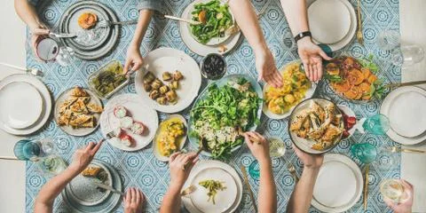 Flat-lay of human hands holding mediterranean starters and drinks Stock Photos