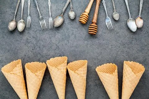 Flat lay ice cream cones collection , spoons ,fork and honey dipper on dark.. Stock Photos
