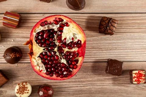 Flat lay image with assorted chocolates and pomegranate on wooden background Stock Photos