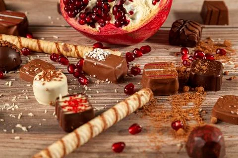 Flat lay image with assorted chocolates and pomegranate on wooden background Stock Photos