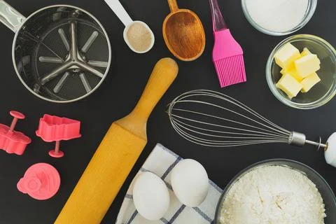 Flat lay ingredients for baking and kitchen utensils on a black background Stock Photos
