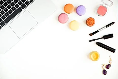 Flat lay of keyboard with macaroons and woman's makeup products Stock Photos