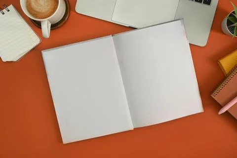 Flat lay laptop computer, cup of coffee, notepad and potted plant on orange Stock Photos