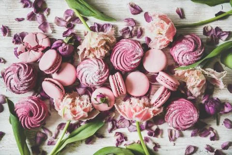 Flat-lay of macaron cookies, marshmallows and flowers over wooden background Stock Photos