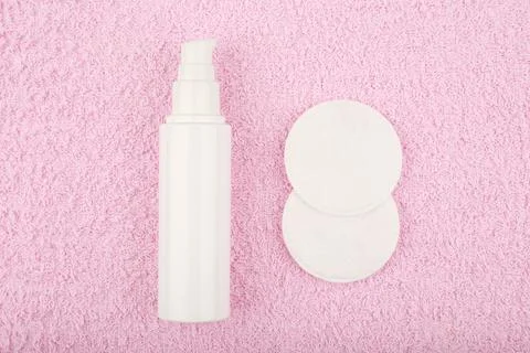 Flat lay with make up removing lotion in white tube and cotton pads on pink Stock Photos