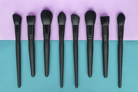 Flat lay of makeup brushes collection on colorful background. Stock Photos