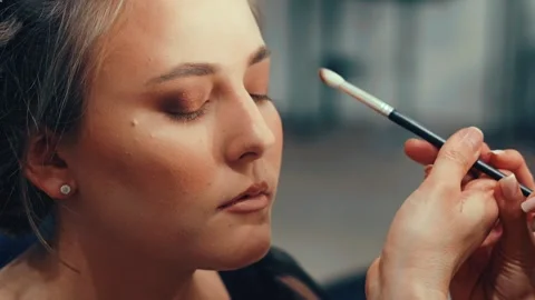 A flat lay of makeup tools and products sets the scene. She picks each item Stock Footage 308747941