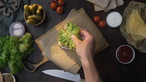 Flat lay of making the sandwich with sliced bacon and salad, chef adds salad to Video stock 117494909