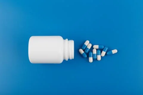 Flat lay with medication bottle and spilled pills on blue background. Concept of Stock Photos