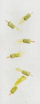 Flat-lay of melting green matcha coconut popsicles over white background Foto stock