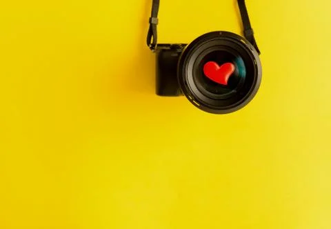 Flat lay of mirorless camera with lens and love red hearts on yellow background Stock Photos