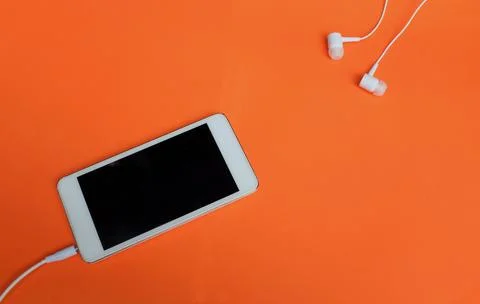 Flat lay modern Smartphone with Blank Screen and Earphones on orange Background Stock Photos