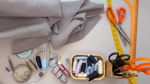 Flat lay muslin fabric, sewing accessories, threads, scissors on cutting table Stock Footage 306561067