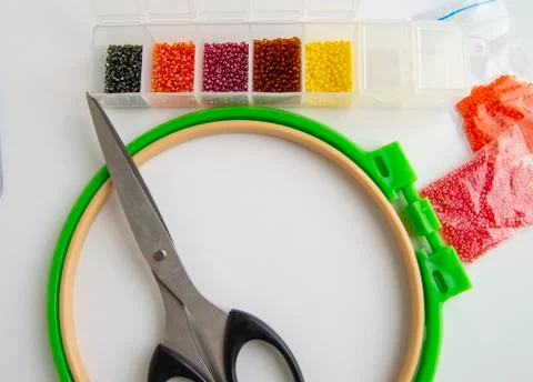 Flat lay needlework and embroidery accessories, scissors hoops and beads on w Stock Photos