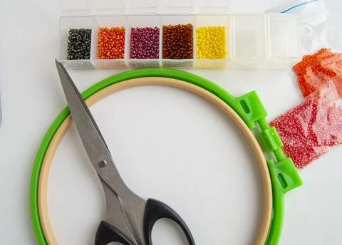 Flat lay needlework and embroidery accessories, scissors hoops and beads on w Stock Photos